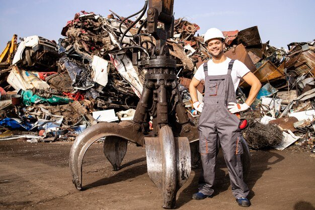 worker-standing-by-hydraulic-industrial-machine-used-lifting-scrap-metal-parts-junk-yard_308072-1473